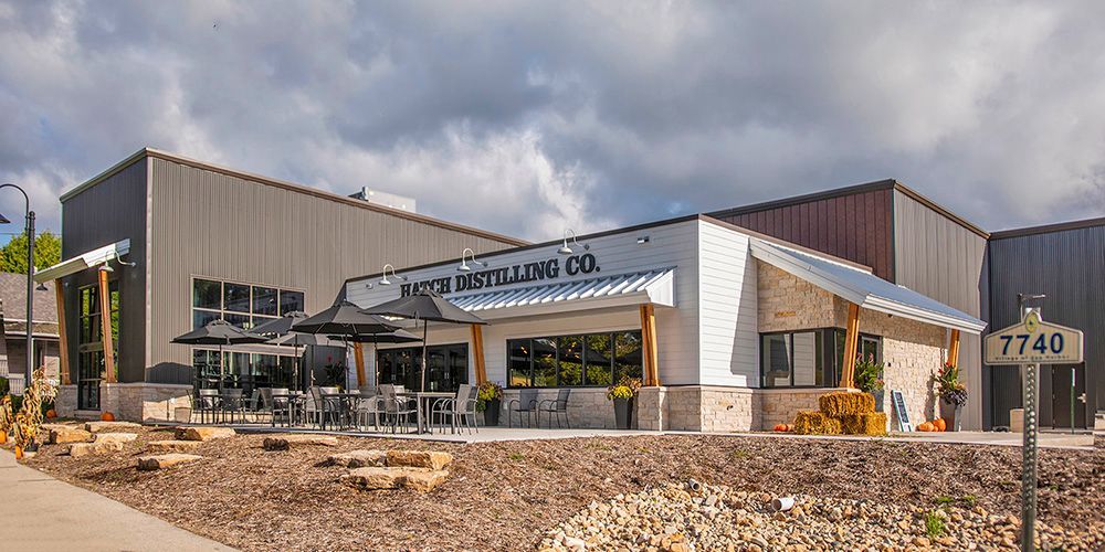 Modern commercial building with a coffee shop sign, outdoor seating, and landscaping near address 7740