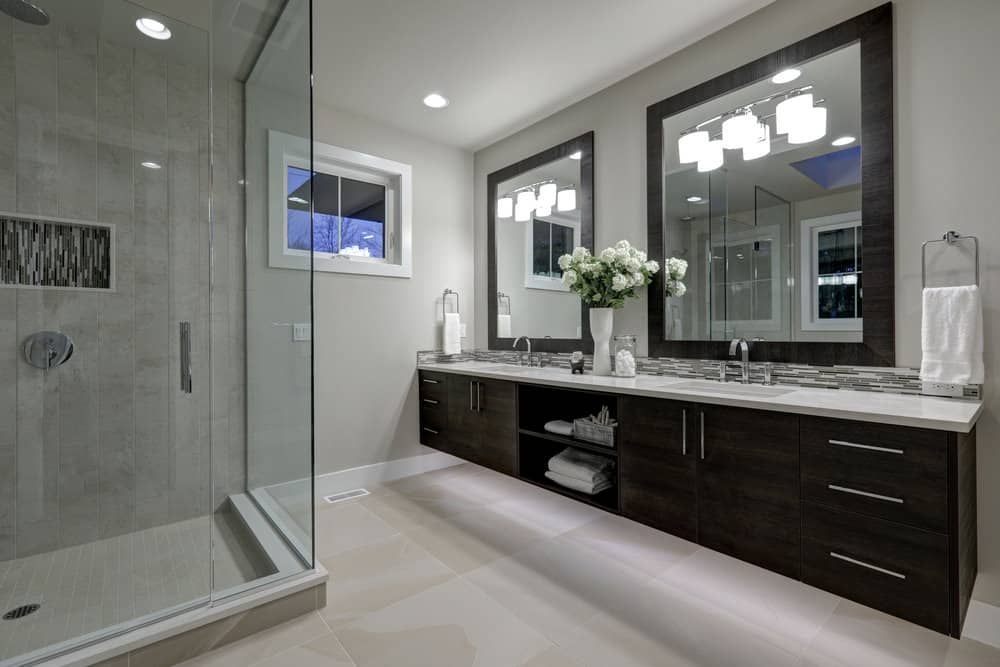 Modern bathroom with glass shower, double vanity, and large mirrors