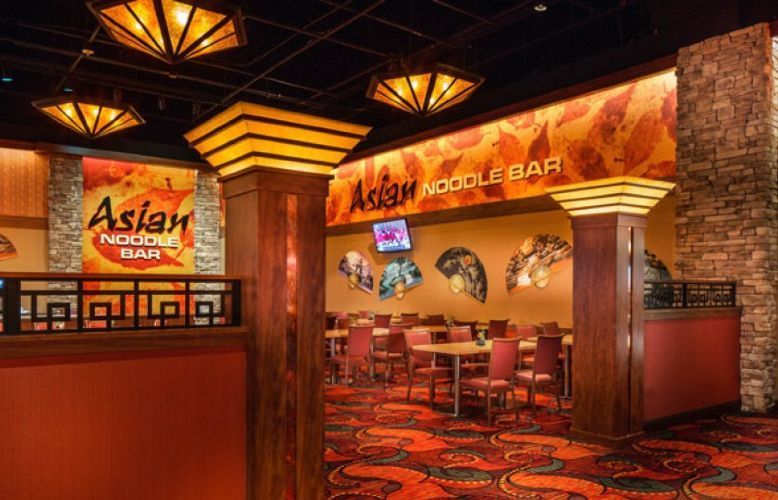 Asian noodle bar interior with red booths, warm lighting, and decorative wall art