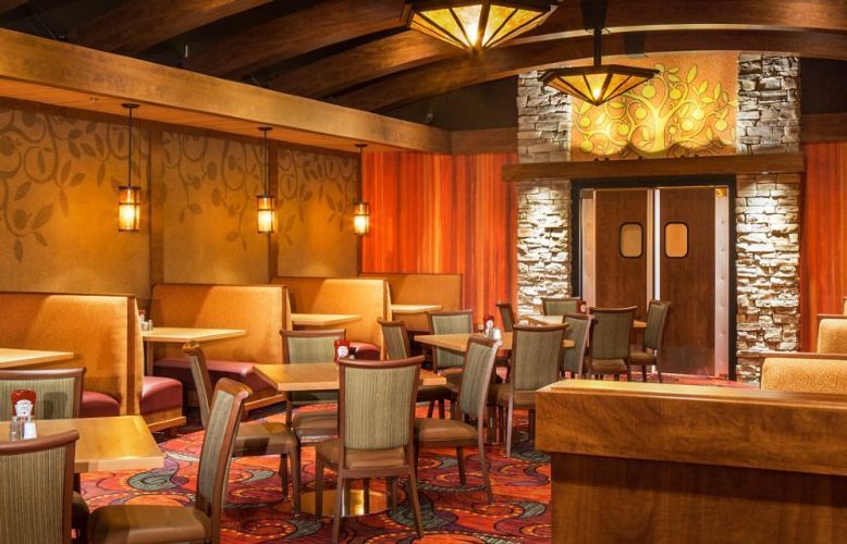 Cozy rustic restaurant lounge with wood-paneled walls, booths, tables, and warm amber lighting