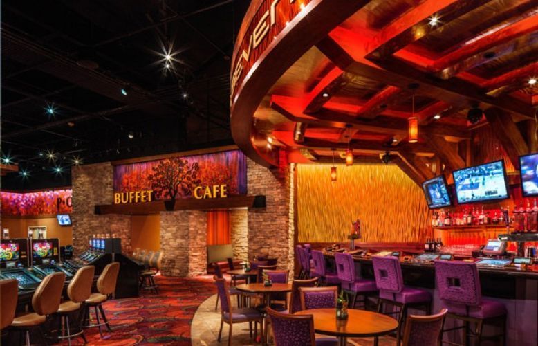 Warm-lit restaurant and bar interior with tables, chairs, and glowing red ceiling accents
