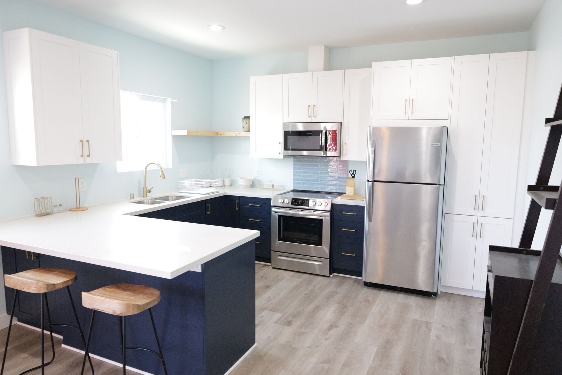 Bright modern kitchen with white cabinets, stainless steel appliances, and a white island with stools