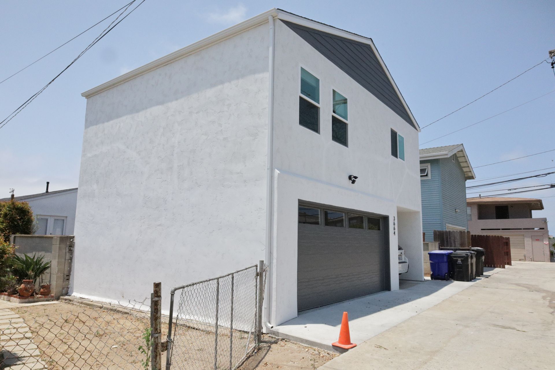 White two-story house with gray garage door on a sunny street corner