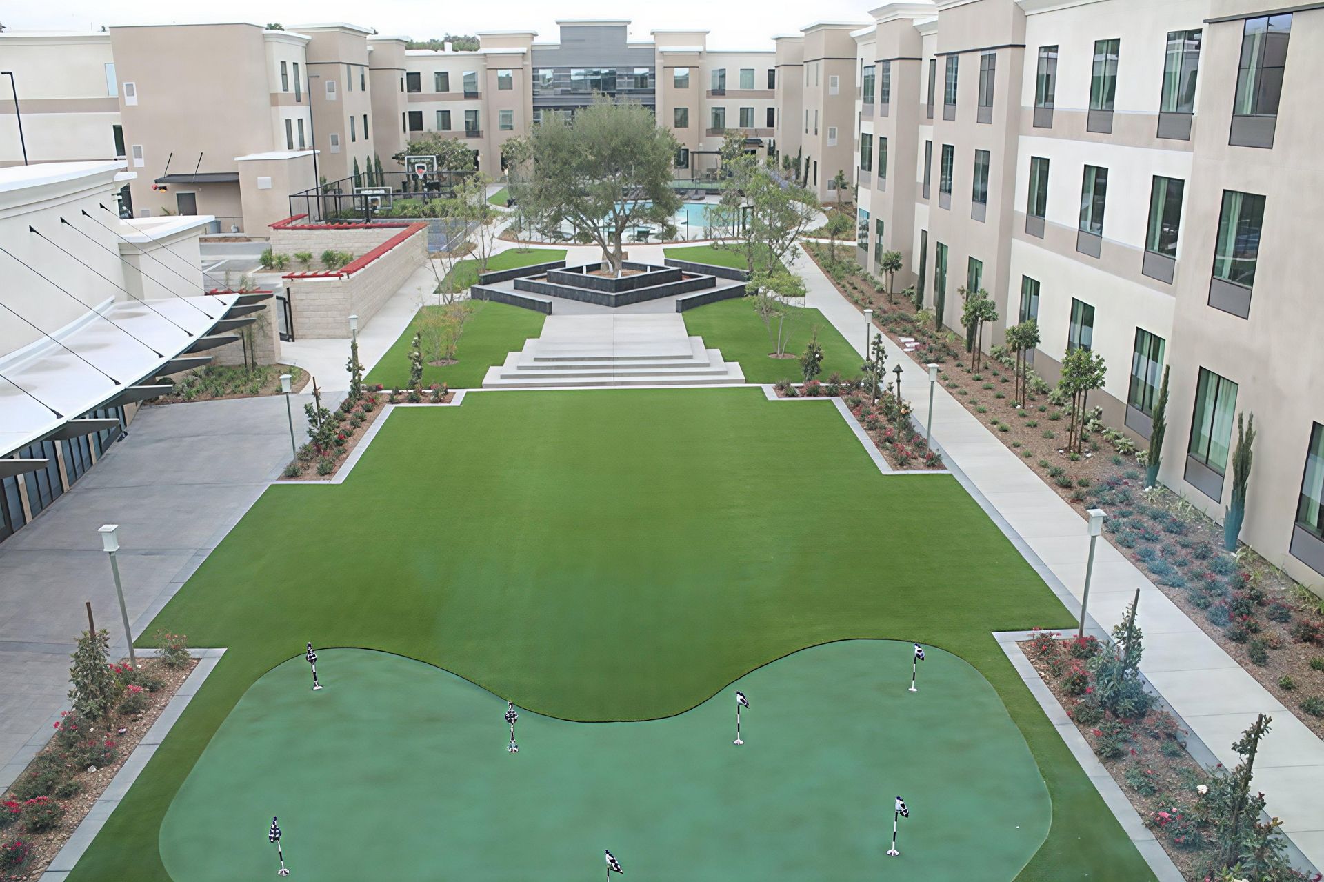 Courtyard with green lawn and putting green between apartment buildings