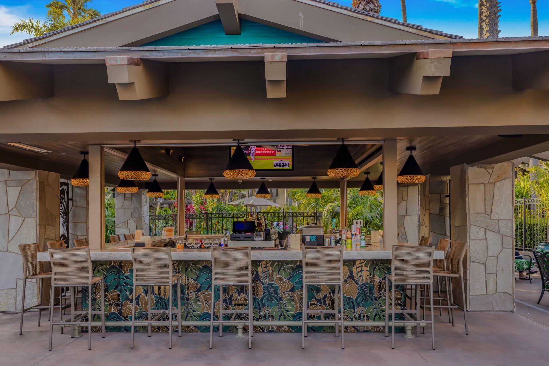 Outdoor patio bar with stools, stone columns, and hanging lights under a covered roof
