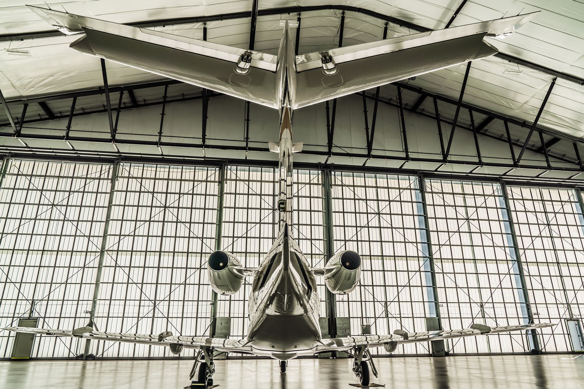 Vintage aircraft displayed in a hangar, viewed from the front with a glass wall backdrop