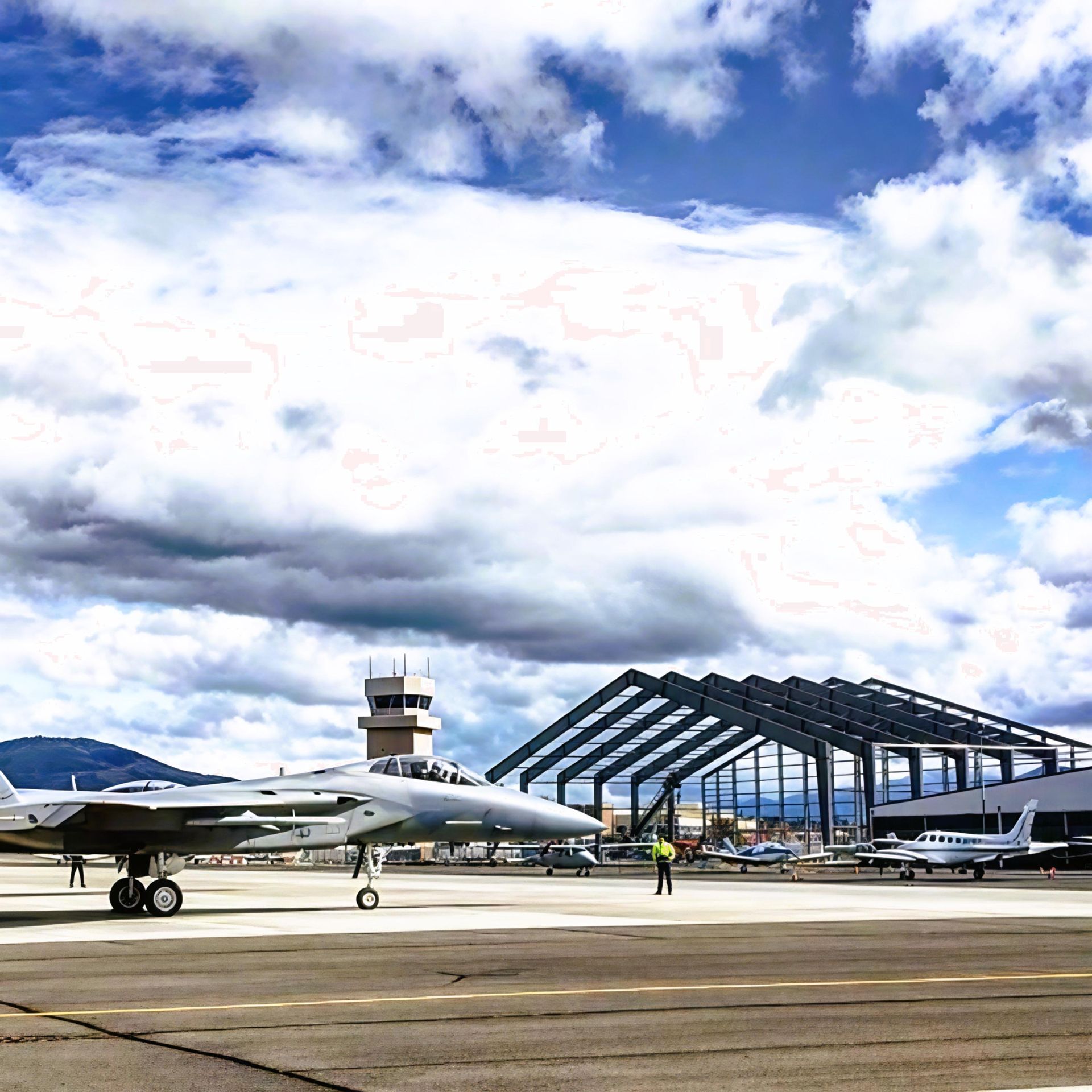 Airplanes parked on a runway beside a small airport terminal under dramatic cloudy sky