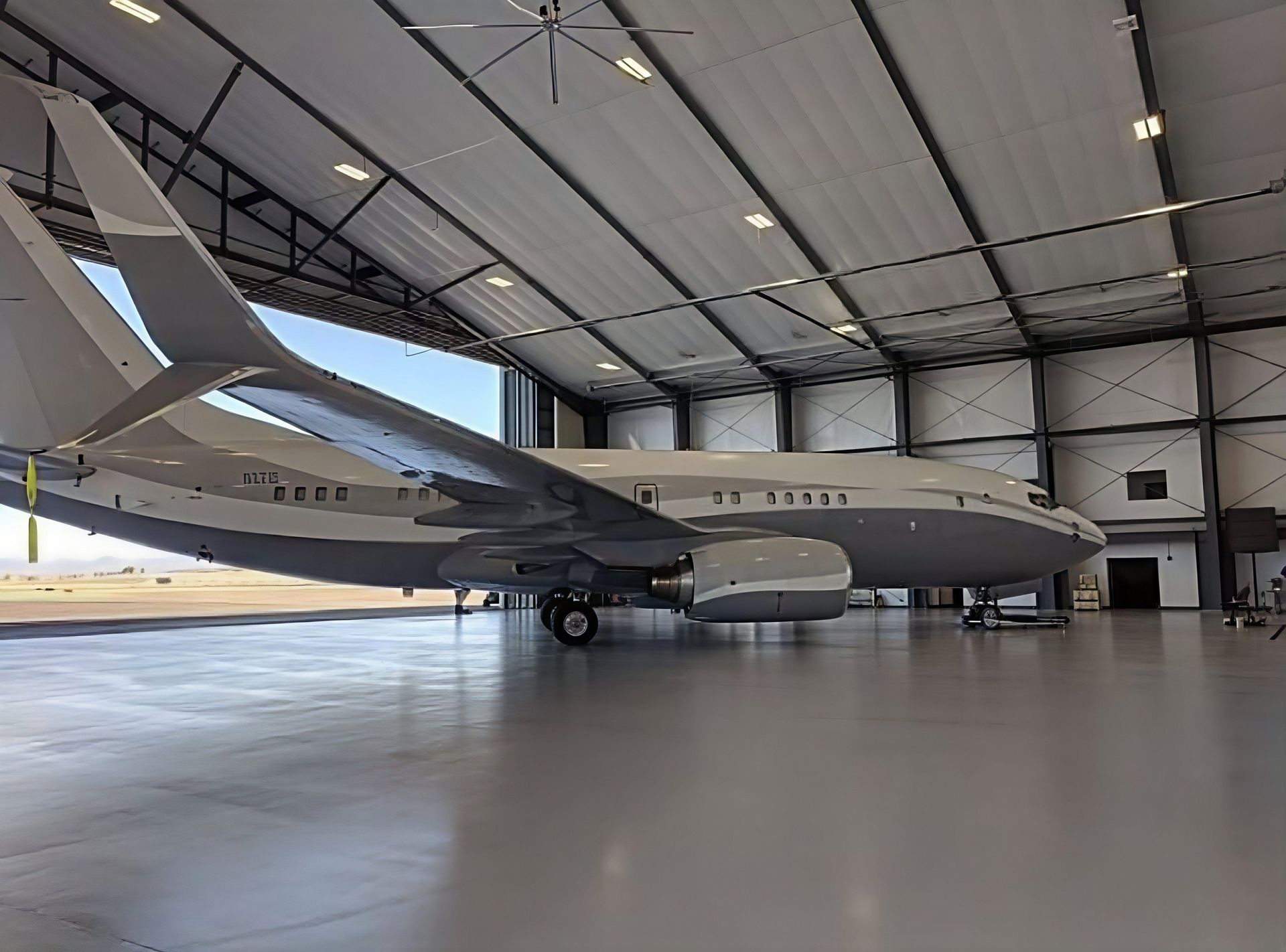 Large gray military jet parked inside a bright aircraft hangar.