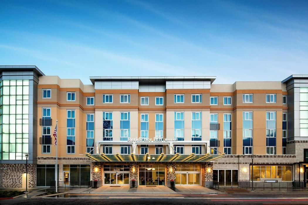 Modern multi-story hotel facade with glass entrance and tan brick exterior at dusk