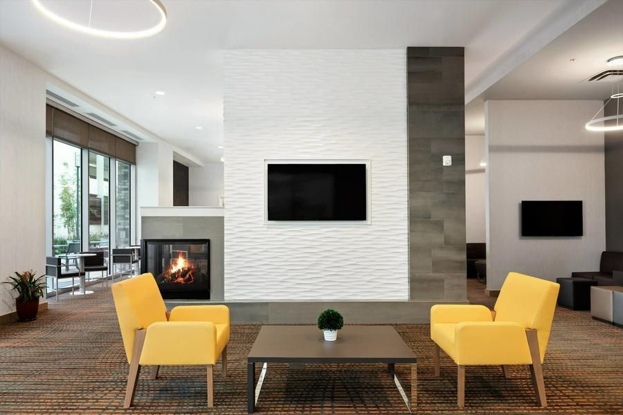 Modern living room with two yellow chairs, a coffee table, fireplace, and wall-mounted TV