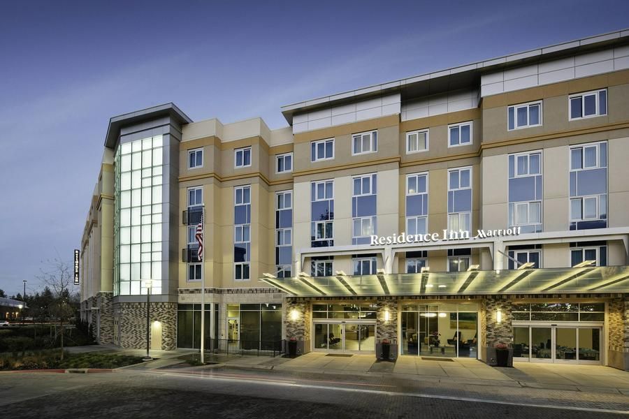 Exterior of a modern hotel with glass entrance, beige facade, and covered drop-off area