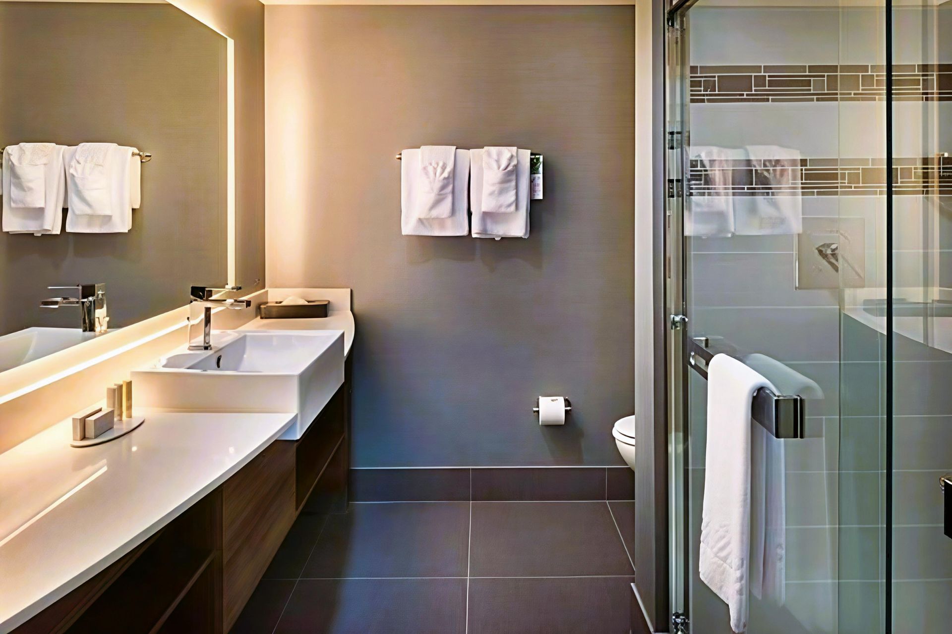 Modern bathroom with double sinks, large mirror, and glass shower enclosure