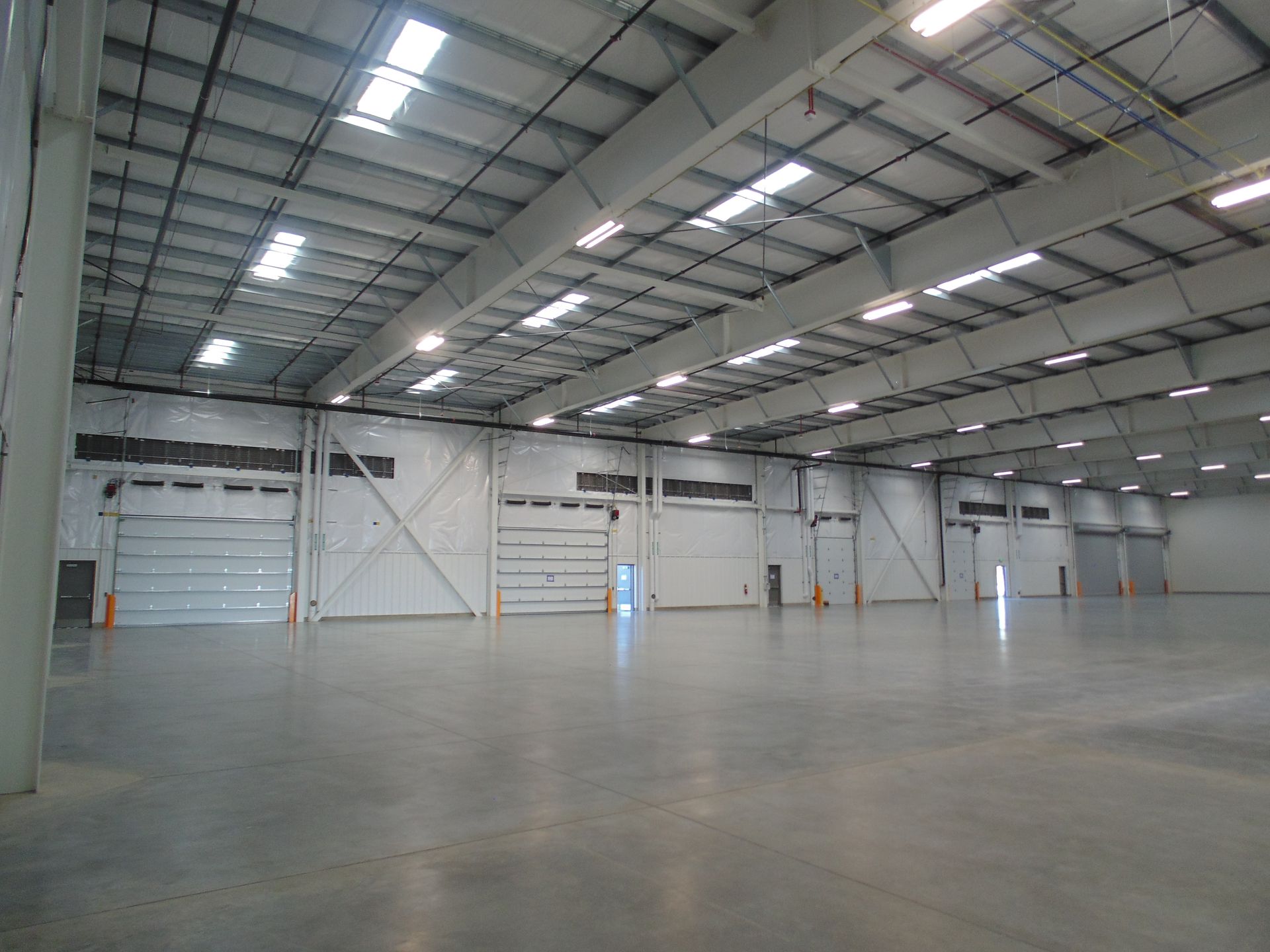 Empty indoor warehouse with a high metal ceiling and polished concrete floor
