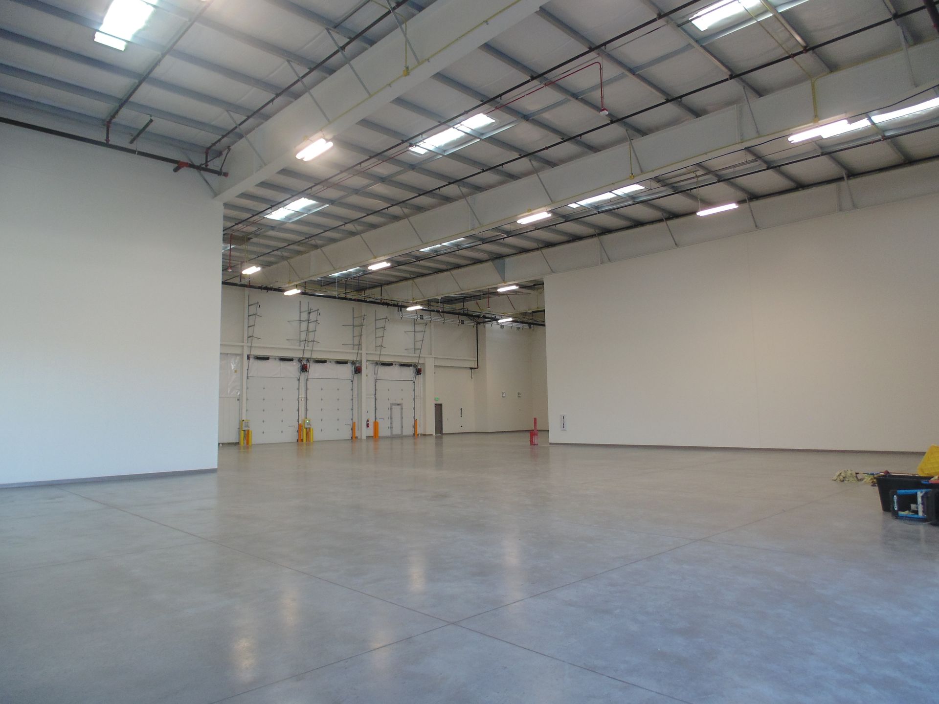Empty warehouse interior with high ceiling, white walls, and polished concrete floor