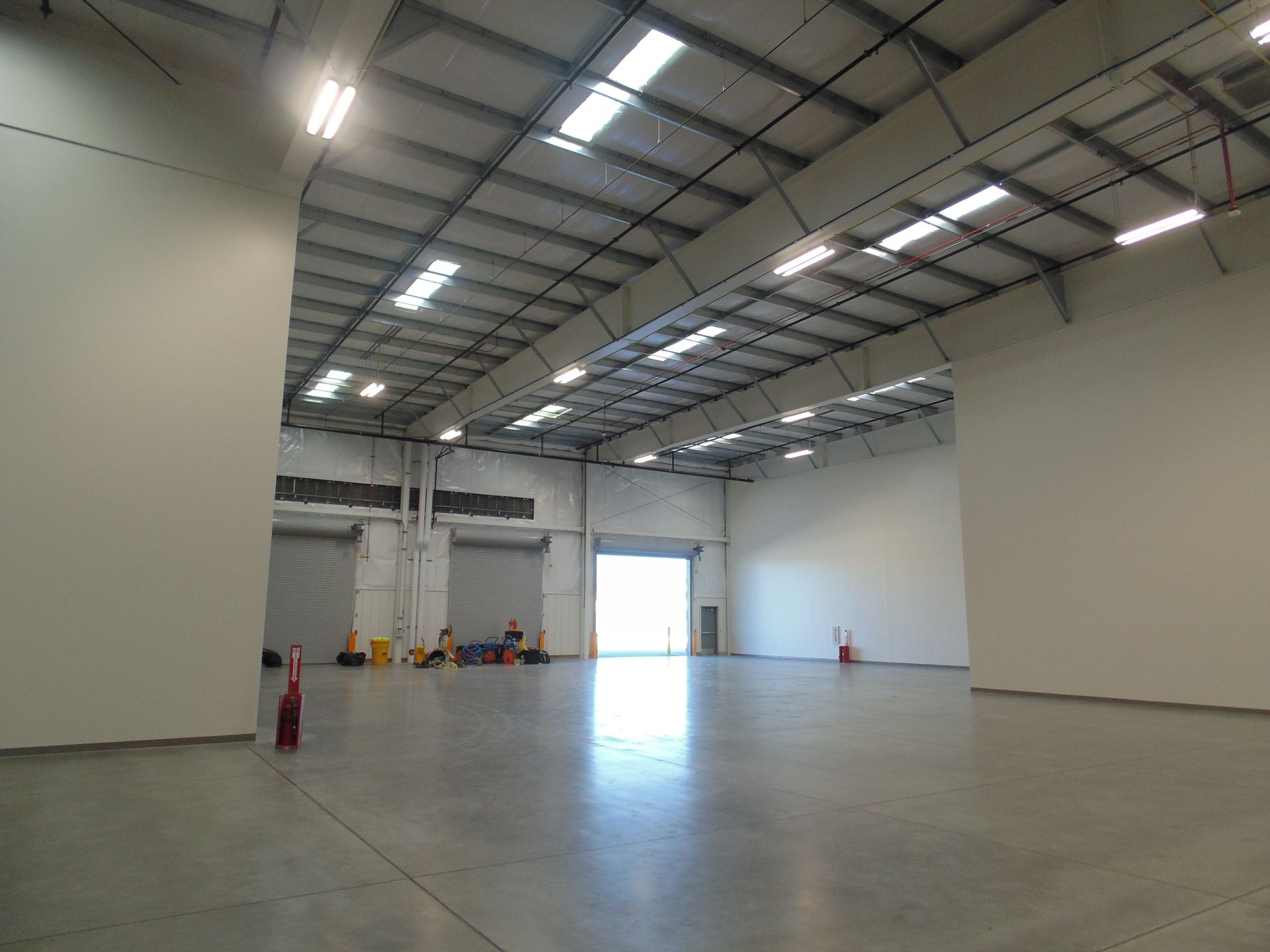 Empty warehouse interior with concrete floor, high ceiling, and bright open doorway