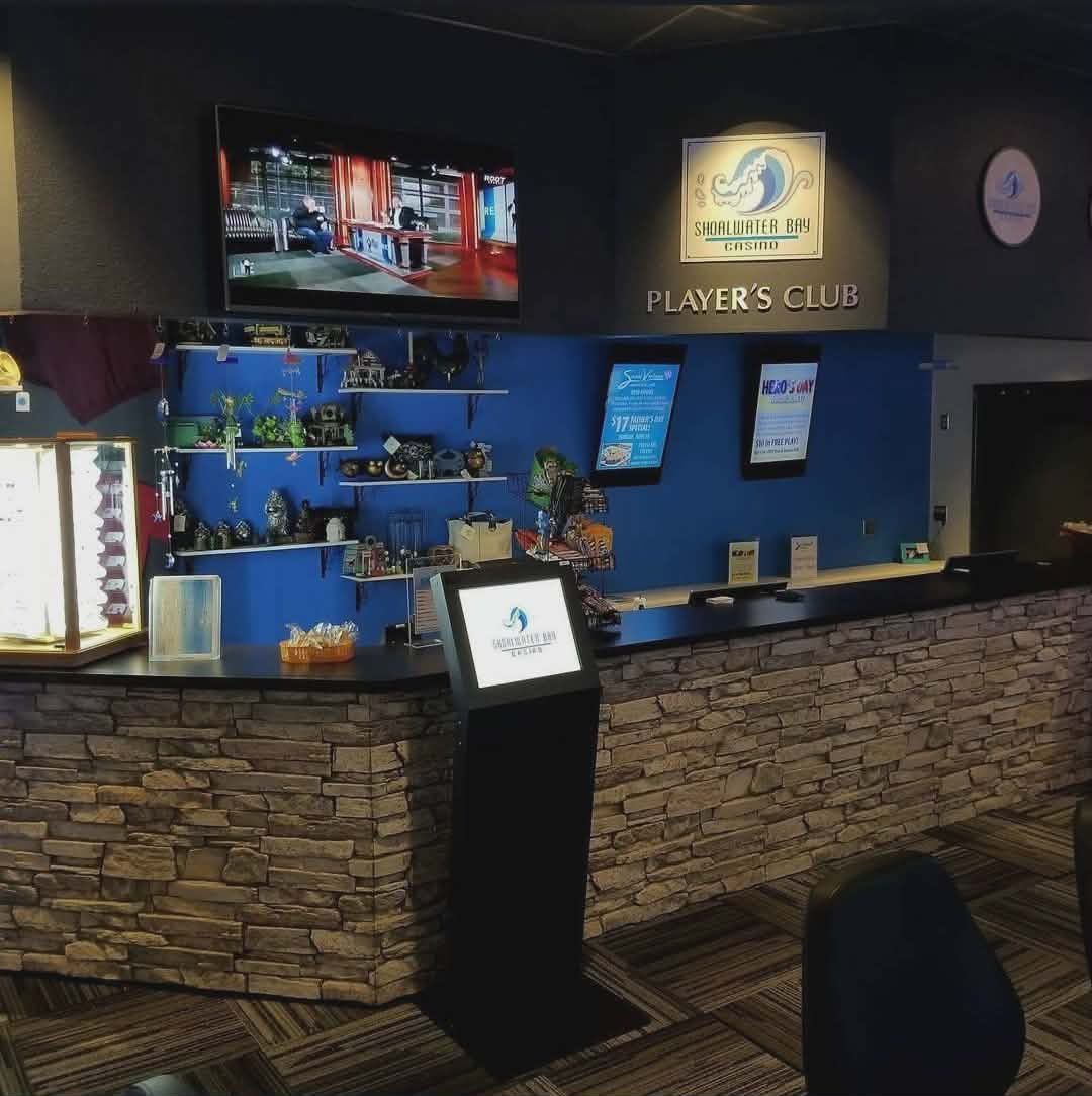 Bar with stone front, blue walls, TV screens, and a lit Player’s Club sign behind the counter
