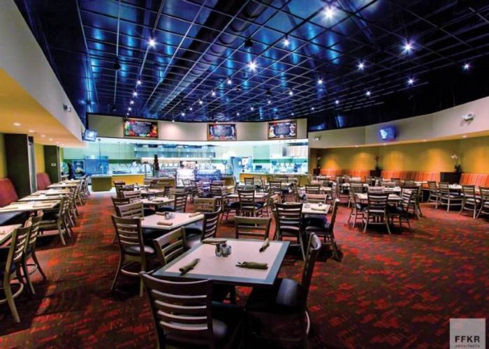 Empty restaurant dining room with tables, chairs, and a red carpet under blue star-like ceiling lights