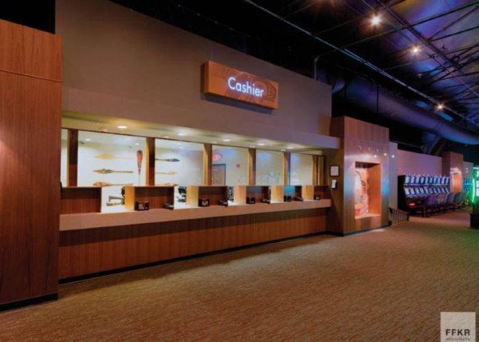 Indoor concession counter with wooden panels and lit service windows in a dark theater-like space
