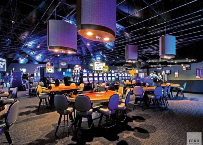Empty bowling alley with glowing lanes, tables, and hanging lights in a dark neon-lit arcade.