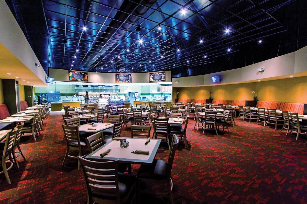 Empty restaurant dining room with red carpet, tables and chairs, and a blue-lit ceiling