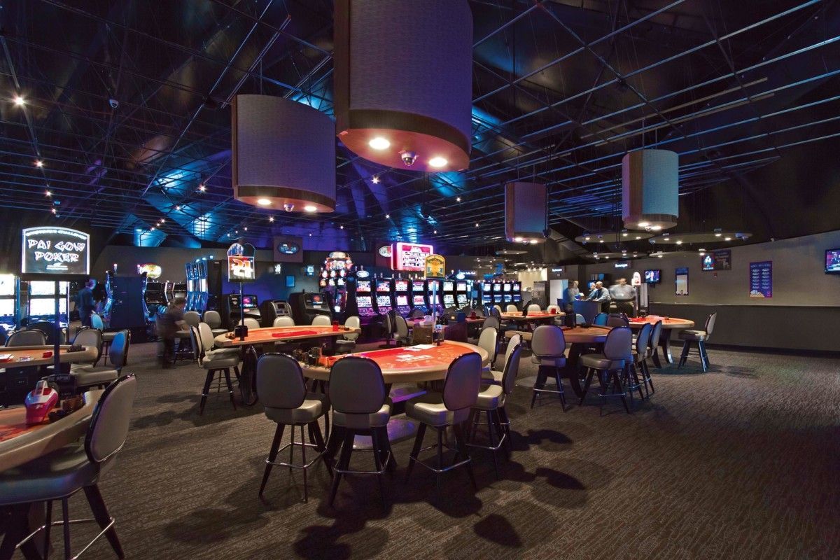 People seated at a dimly lit arcade or bowling alley with colorful neon lights and game screens.