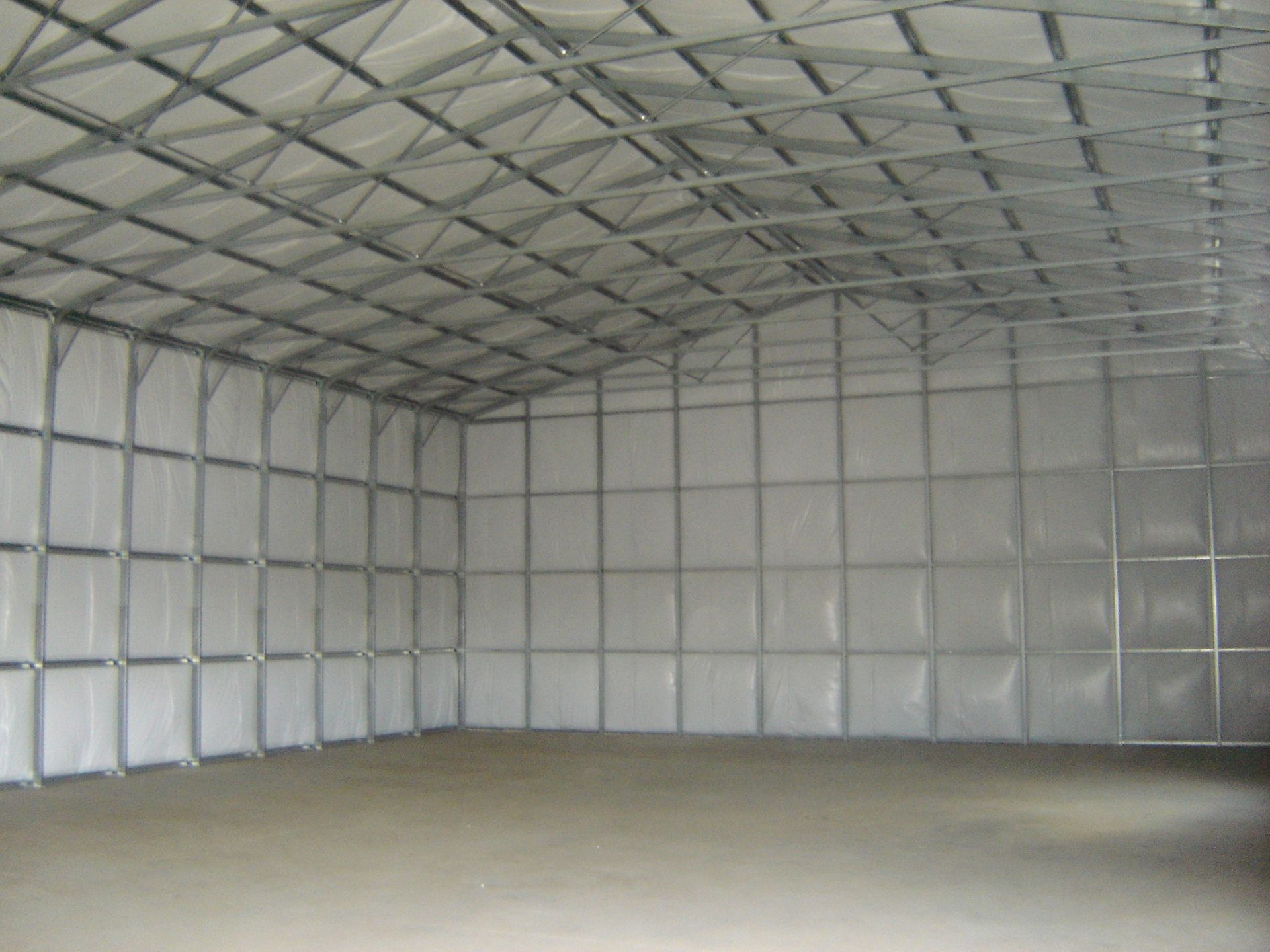 Empty metal warehouse with a high corrugated roof and concrete floor