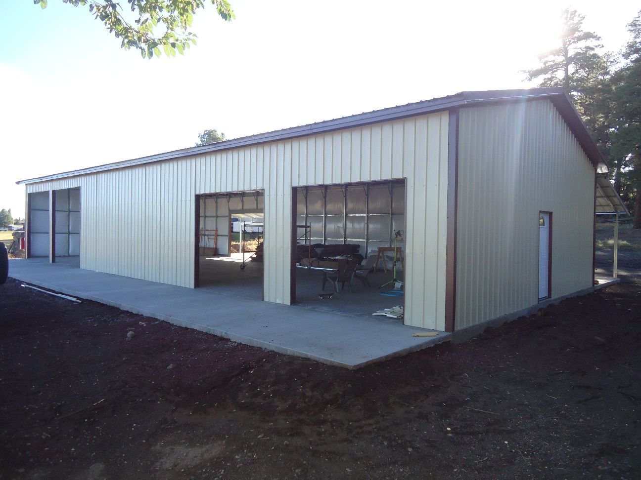 White metal garage or workshop building with large open doors and a concrete apron