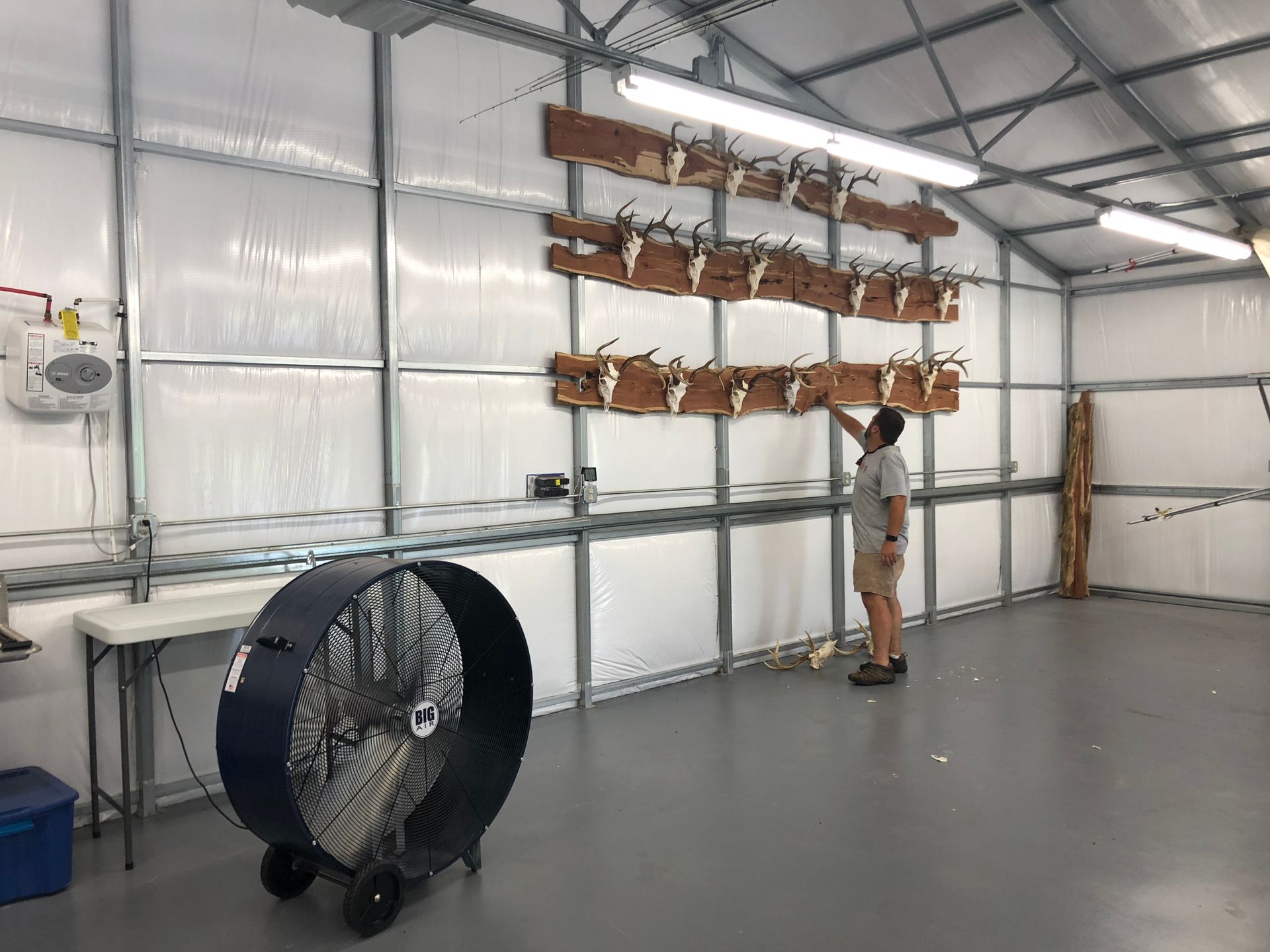 Person adjusting a row of mounted wooden racks in a large industrial workshop