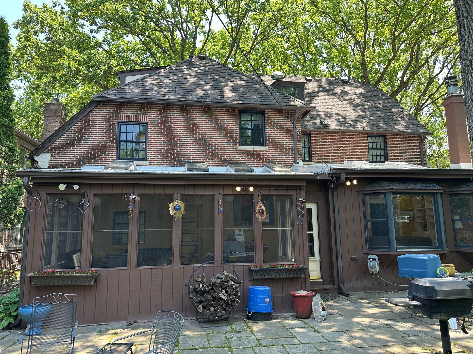 Brick house with screened porch and trees in a wooded yard
