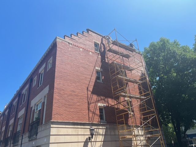 Brick building with scaffolding on the side under a clear blue sky