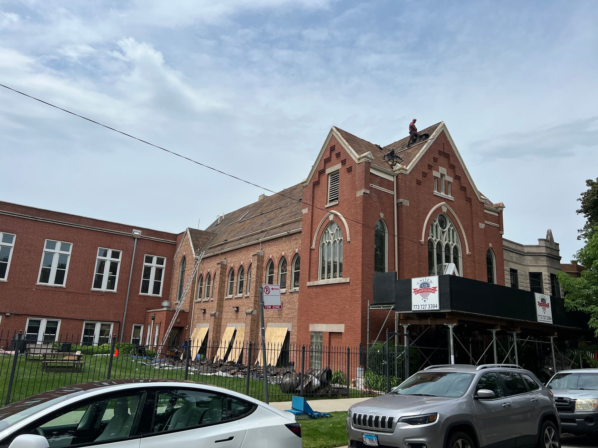 Red brick historic building with arched windows and parked cars on a street corner