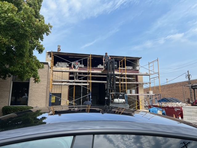 Scaffolding around a two-story house under construction, with a black SUV in the foreground.