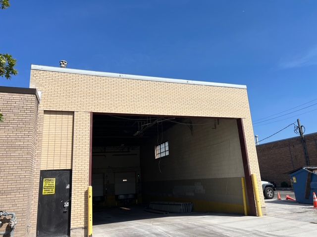 Brick warehouse with a large open loading bay and yellow safety posts under a blue sky