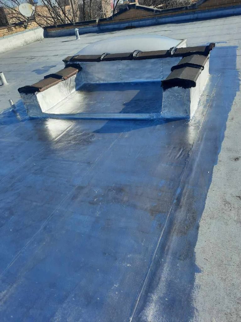 Rooftop skylight with a black metal cover on a reflective blue roof.