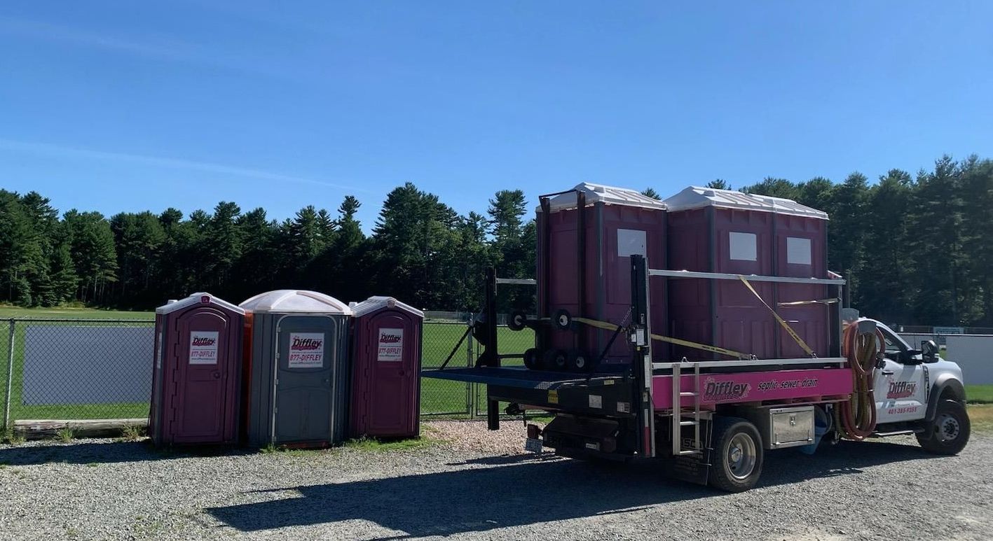 Pink portable toilets on a trailer and 3 portable toilets on the ground