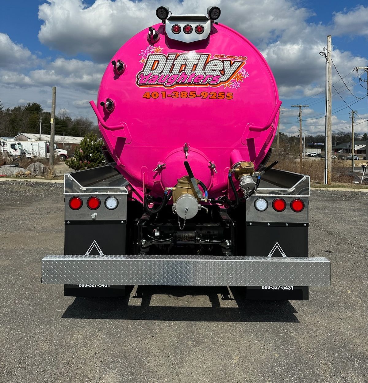 A pink vacuum truck is parked in a parking lot.