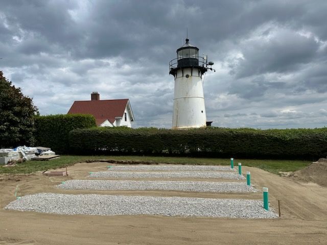 A lighthouse is sitting on top of a hill next to a house.