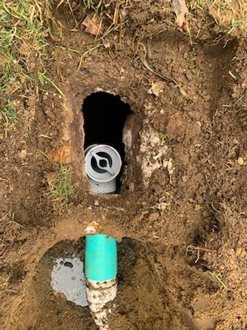 A green pipe is coming out of a hole in the ground.