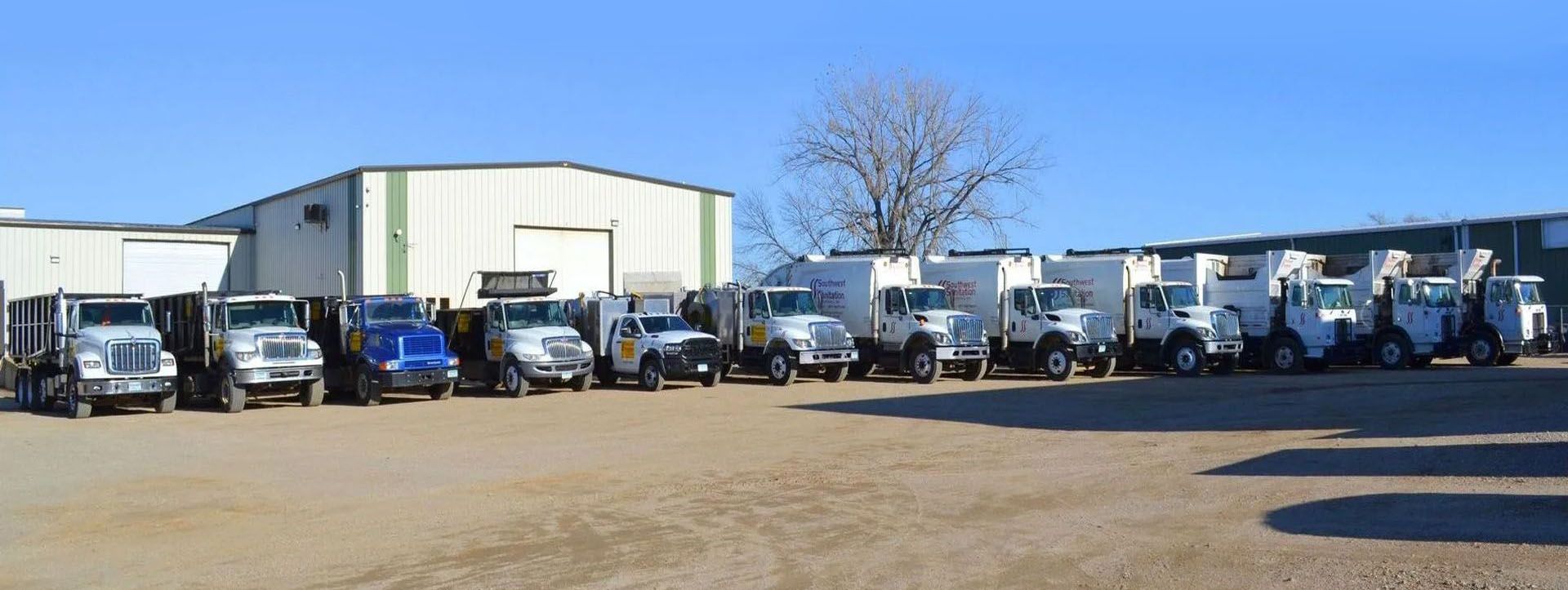 A row of trucks parked in front of a warehouse on a sunny day.
