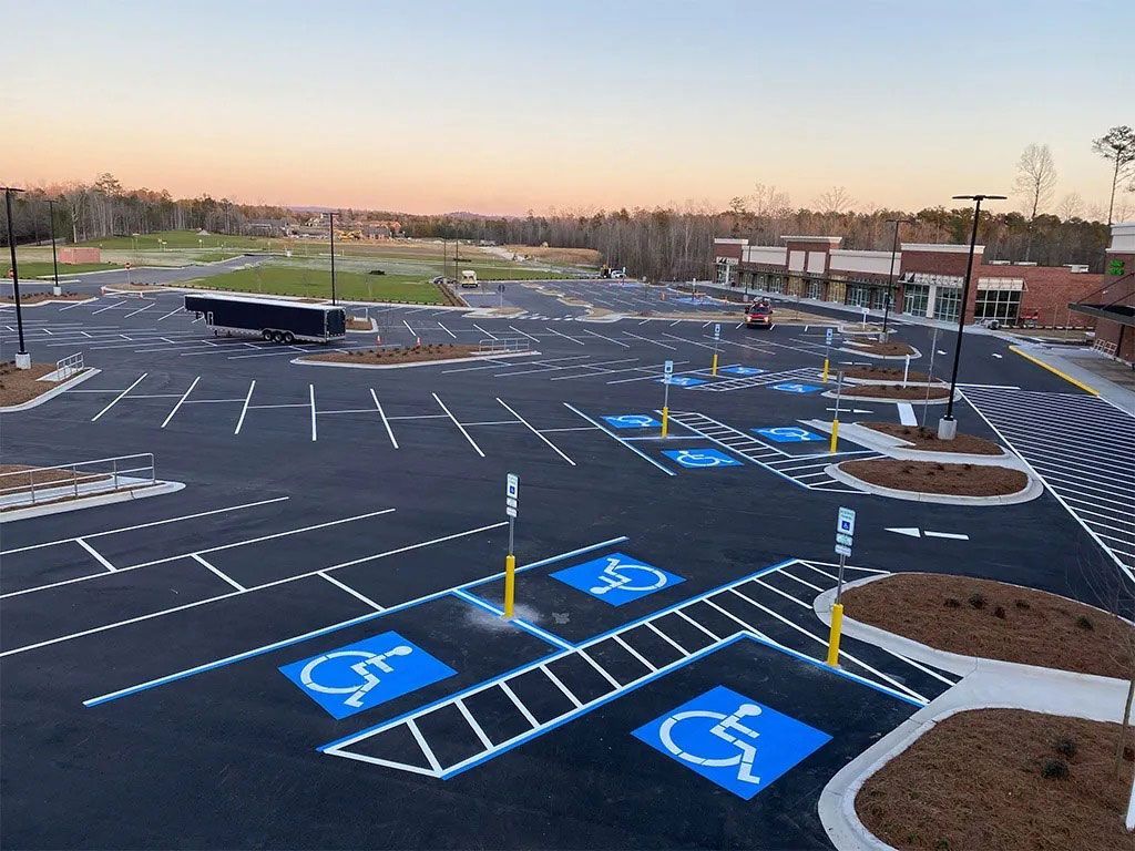 Empty parking lot with fresh blue handicap spaces and white striped markings at sunset