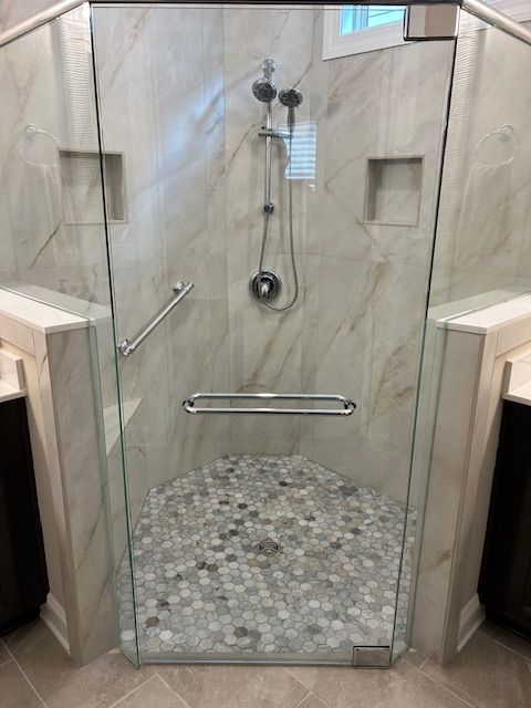 A bathroom with a walk in shower with a glass door.