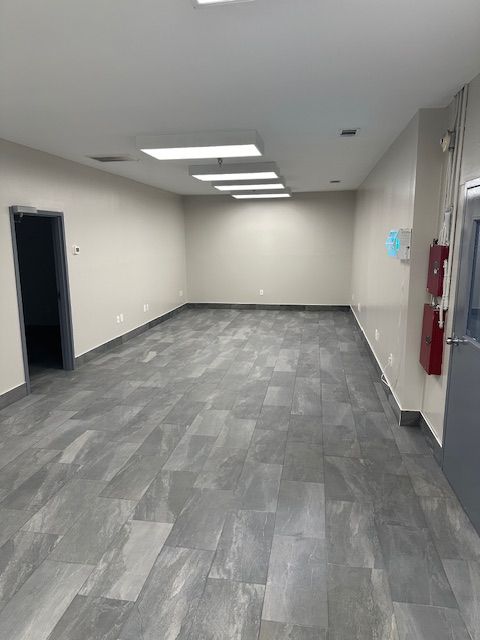 A large empty room with a fire extinguisher on the wall.