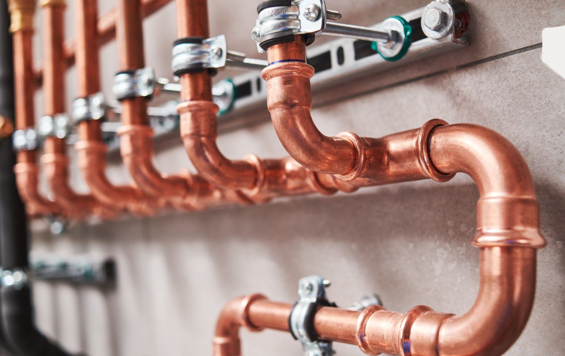 Copper pipes connected to a wall, supported by brackets.