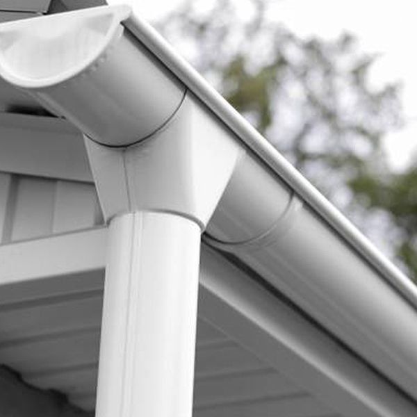White guttering system on a building's edge, angled downwards with a vertical pipe.