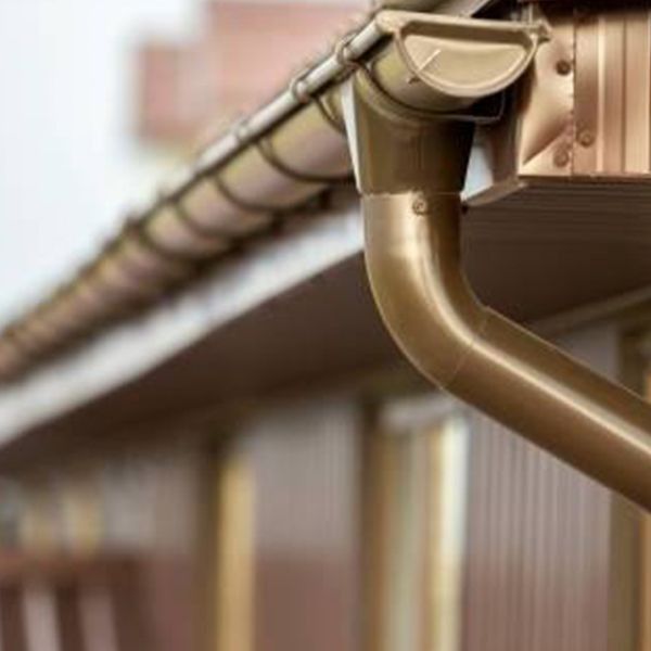 Brown gutters and downspout on a building, protecting the roof from water damage.