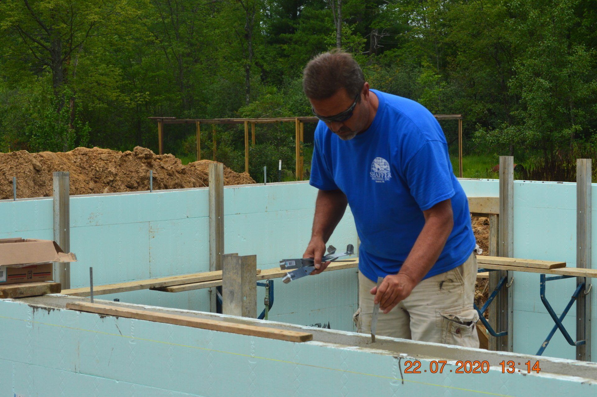 A man in a blue shirt is measuring a piece of wood
