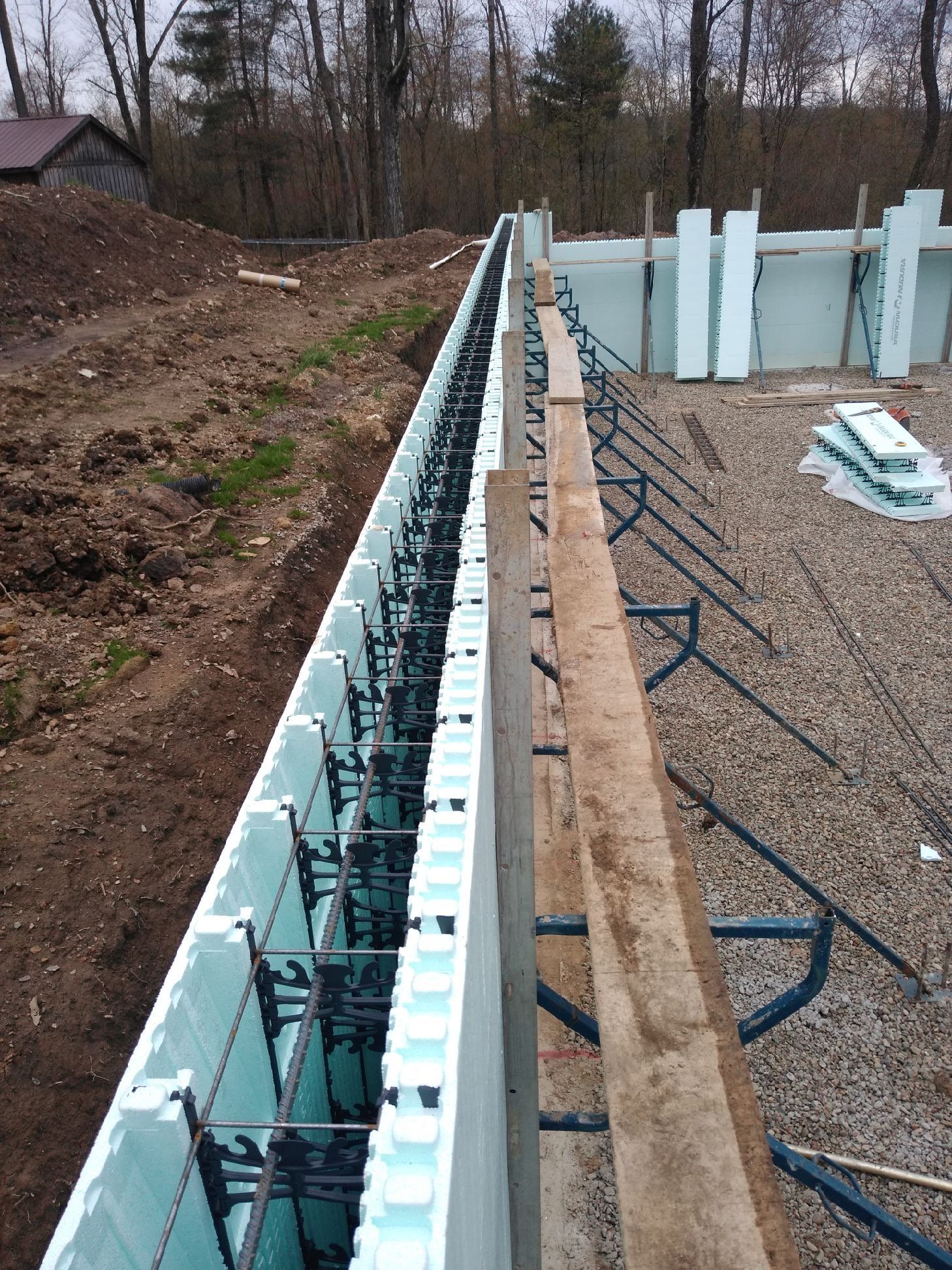 A concrete wall is being built on a dirt field