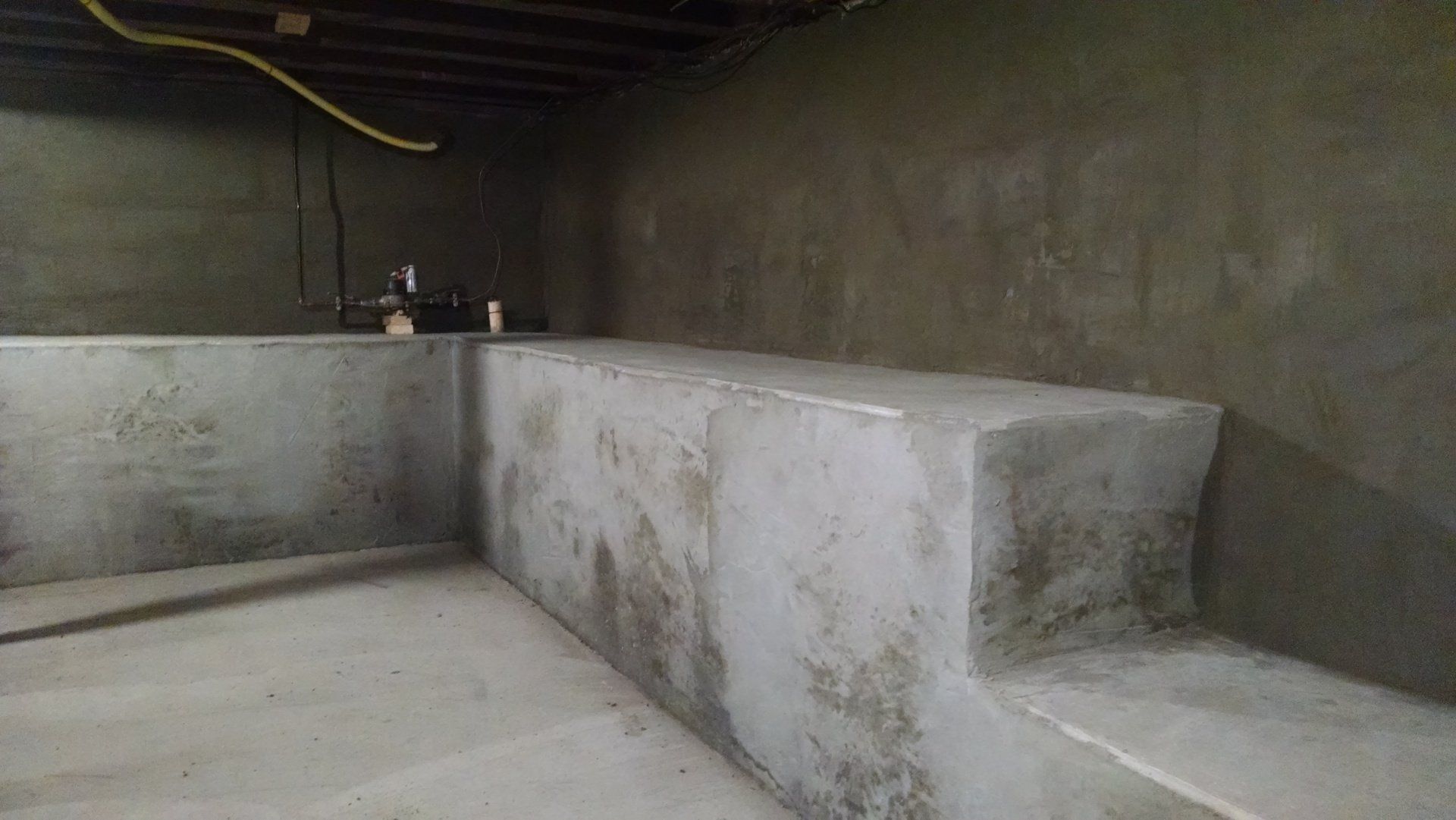 A concrete wall in a basement with a staircase leading up to it