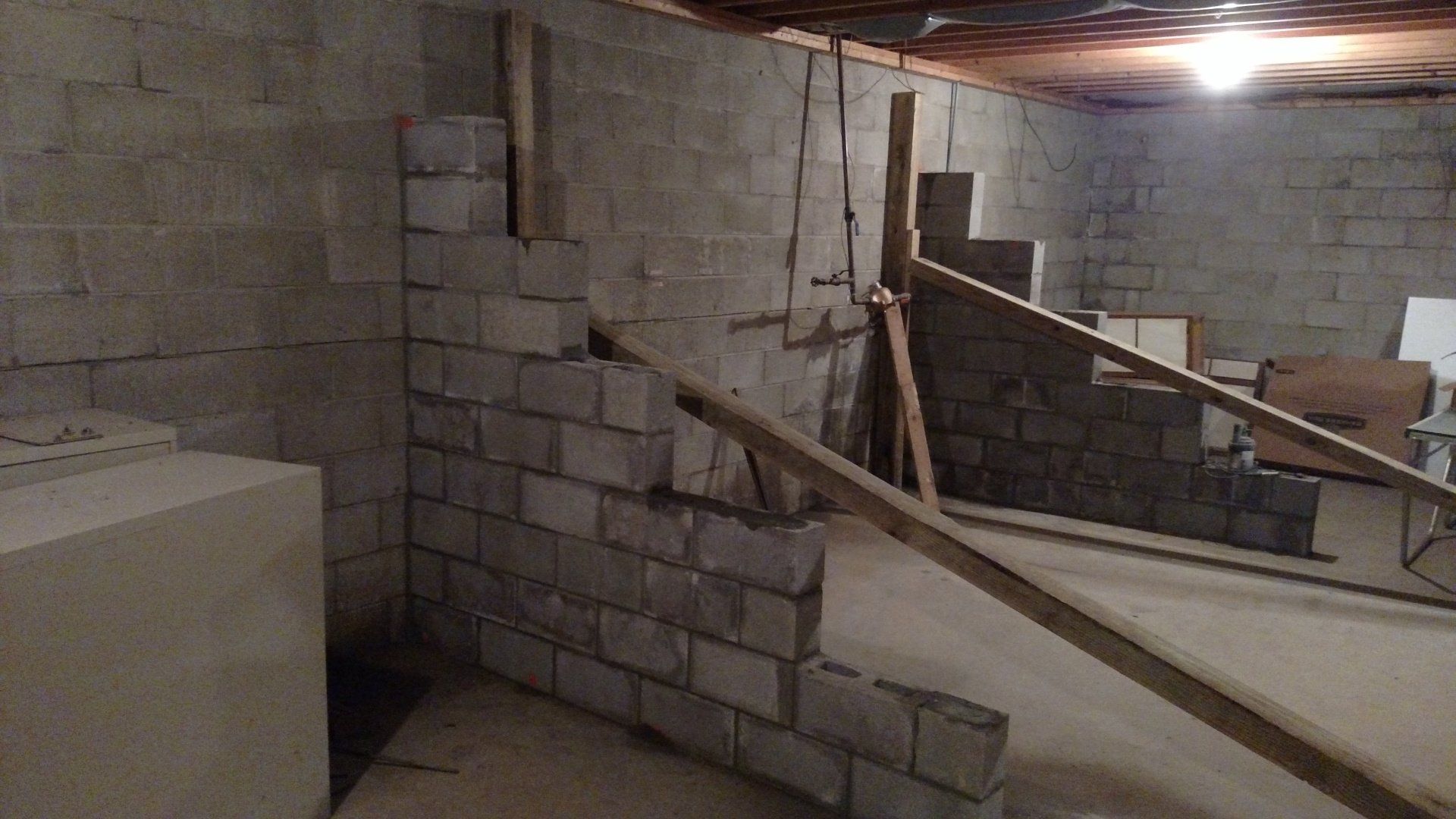 A brick wall in a basement with a wooden railing