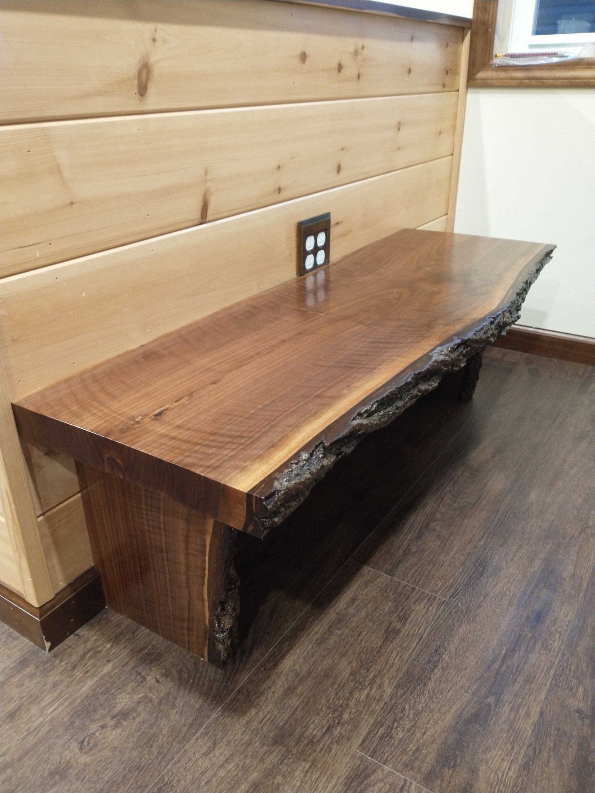 A wooden bench is sitting on a wooden floor next to a wooden wall